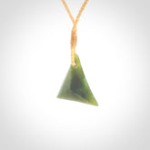 This is a lovely New Zealand Jade, pounamu triangle drop pendant. Hand carved for us by Ric Moor. It is bound with an adjustable beige coloured cord which is length adjustable. Free worldwide shipping.